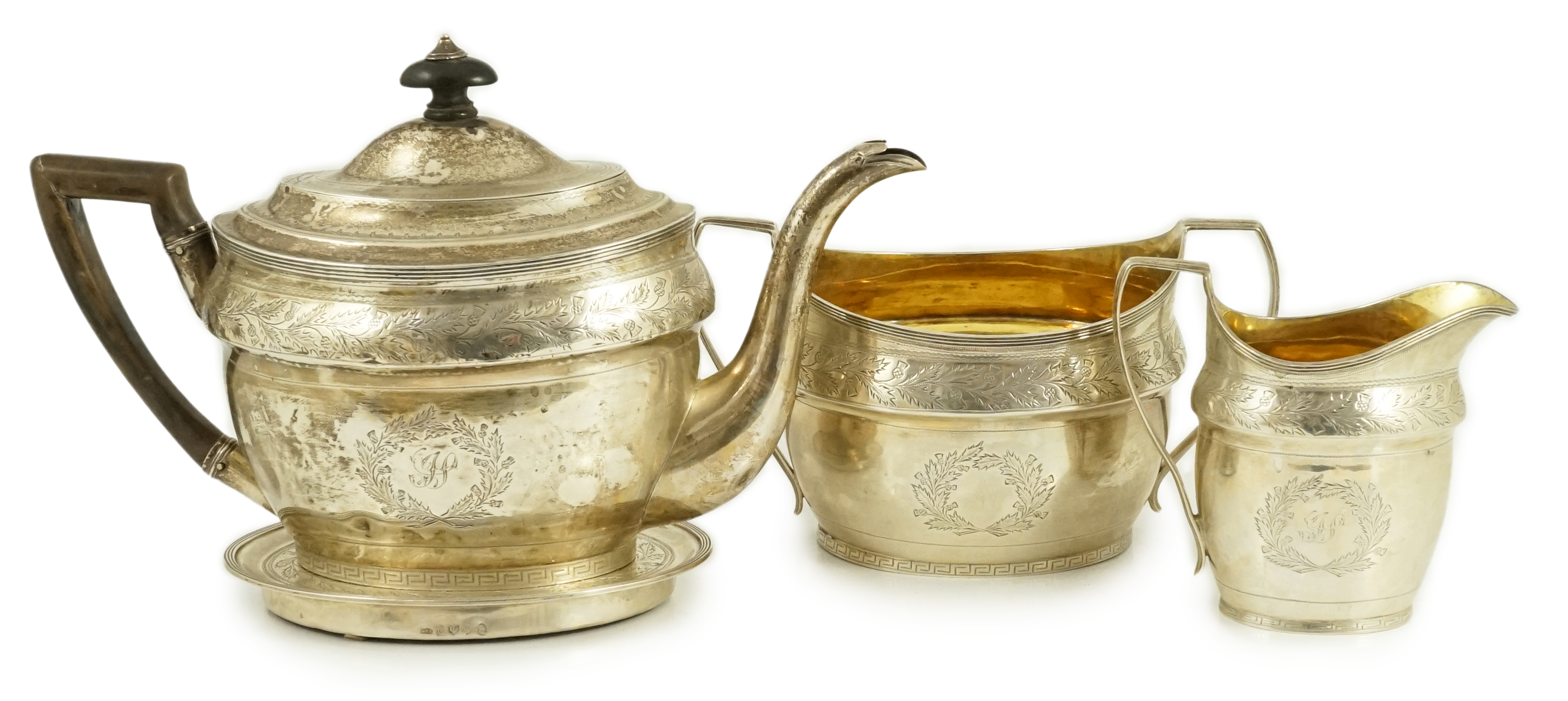A George III Scottish chased silver oval three piece tea set and teapot stand, by William & Patrick Cunningham
